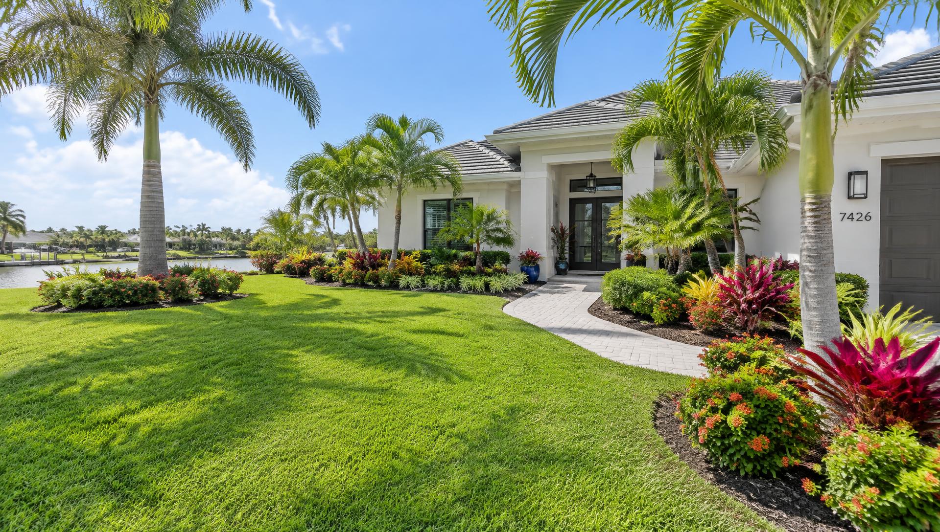 Manicured Florida front yard with palms and paver walkway by Green Affects